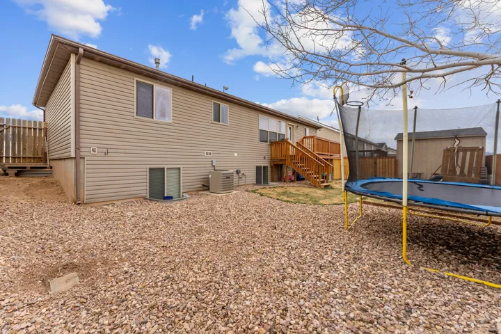 Rear exterior featuring beige horizontal siding, a multi-level wood deck, and a sliding glass door