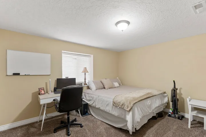 Carpeted room with a ceiling-mounted light fixture, neutral-toned walls, and a window with blinds