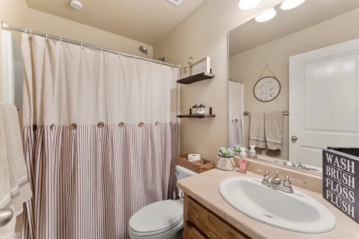 Bathroom featuring a wood-finish vanity with an integrated sink and counter, a large wall-mounted mirror, and a full shower/tub combination