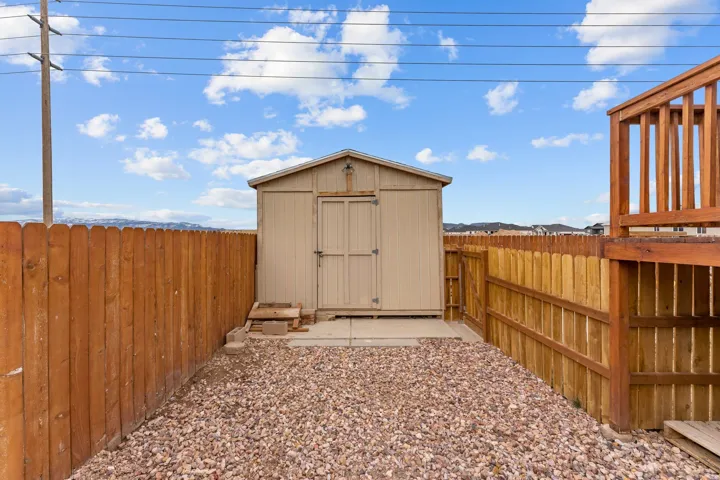 Freestanding utility shed on a concrete pad, surrounded by a wooden privacy fence