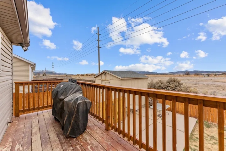 Expansive wood deck with a natural finish, featuring a wooden railing and a beige siding exterior