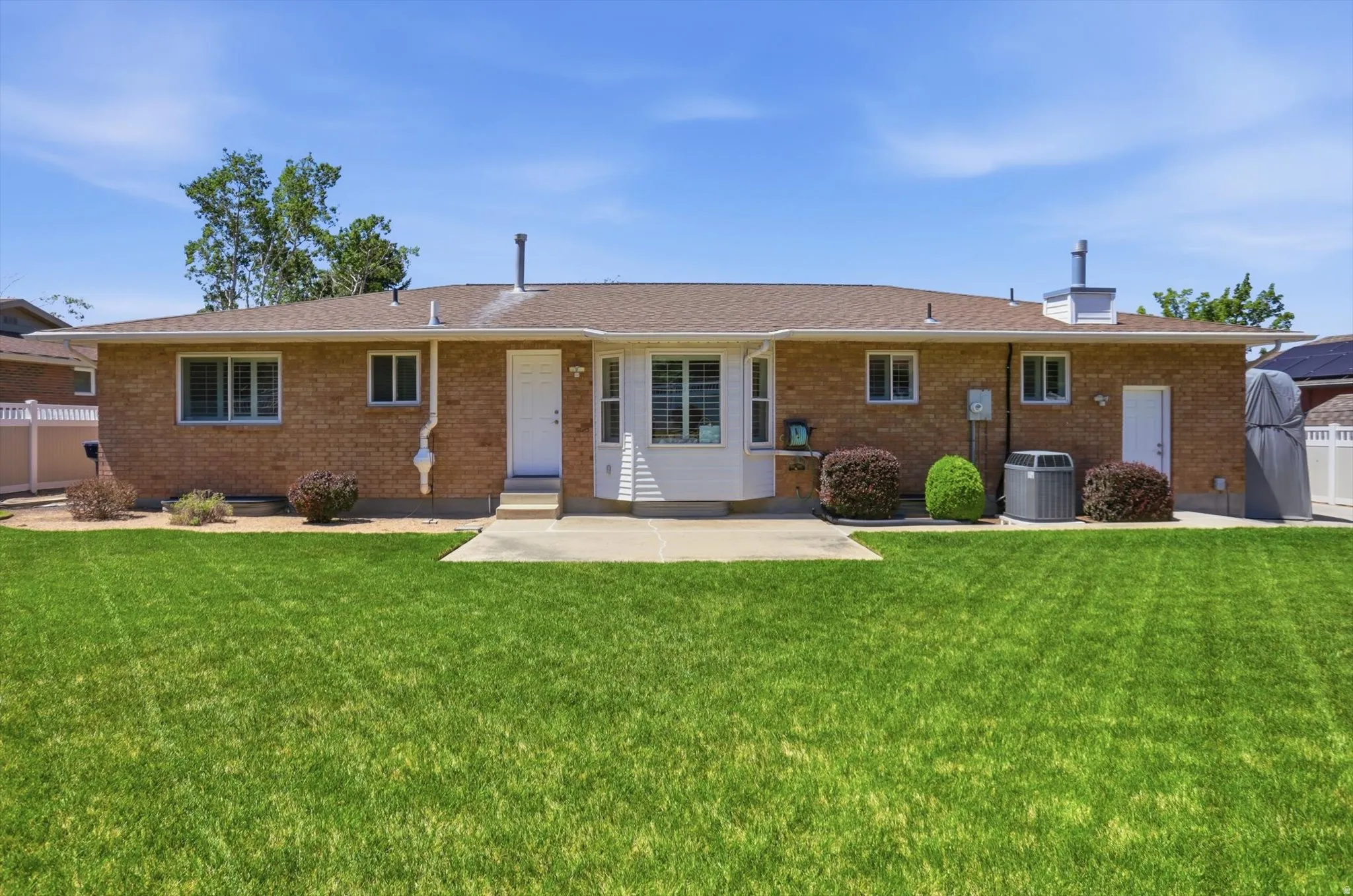 Expansive backyard featuring a manicured lawn and a brick exterior