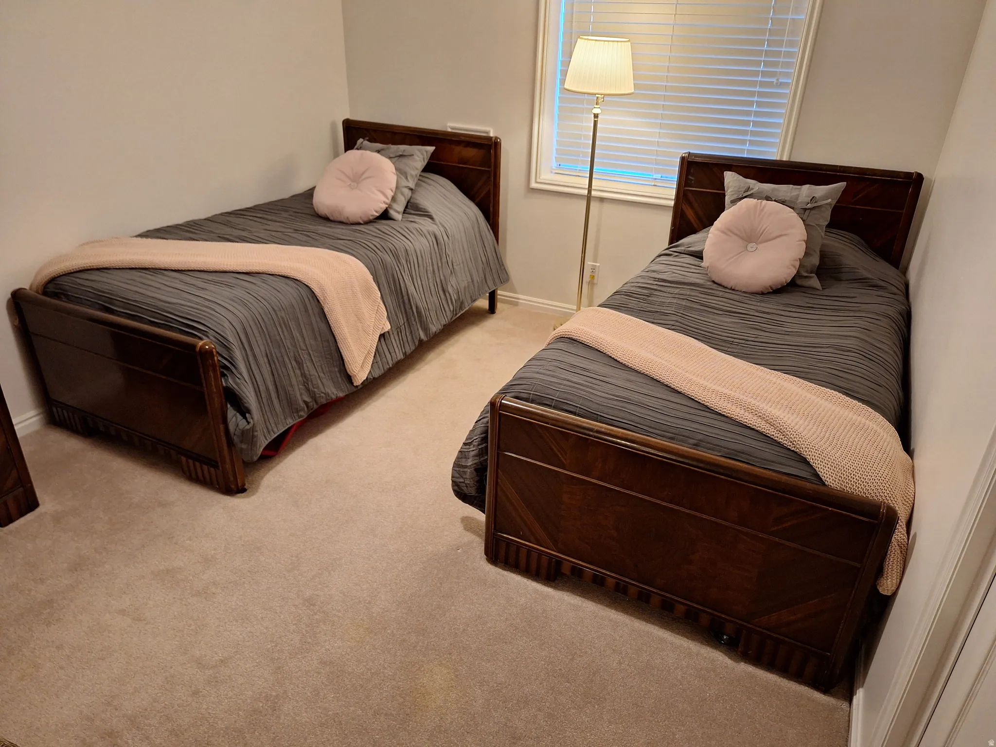 Bright interior room featuring a window with blinds, light-colored walls, and carpet flooring