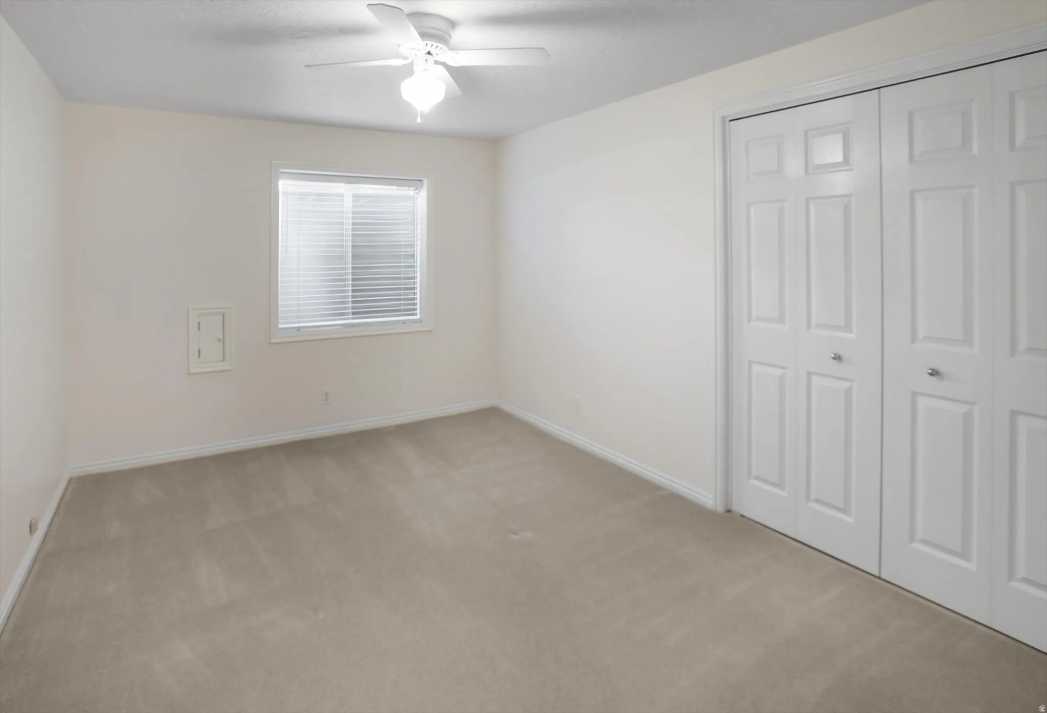 Bright room featuring neutral-toned carpet flooring, white baseboards, and a window with blinds