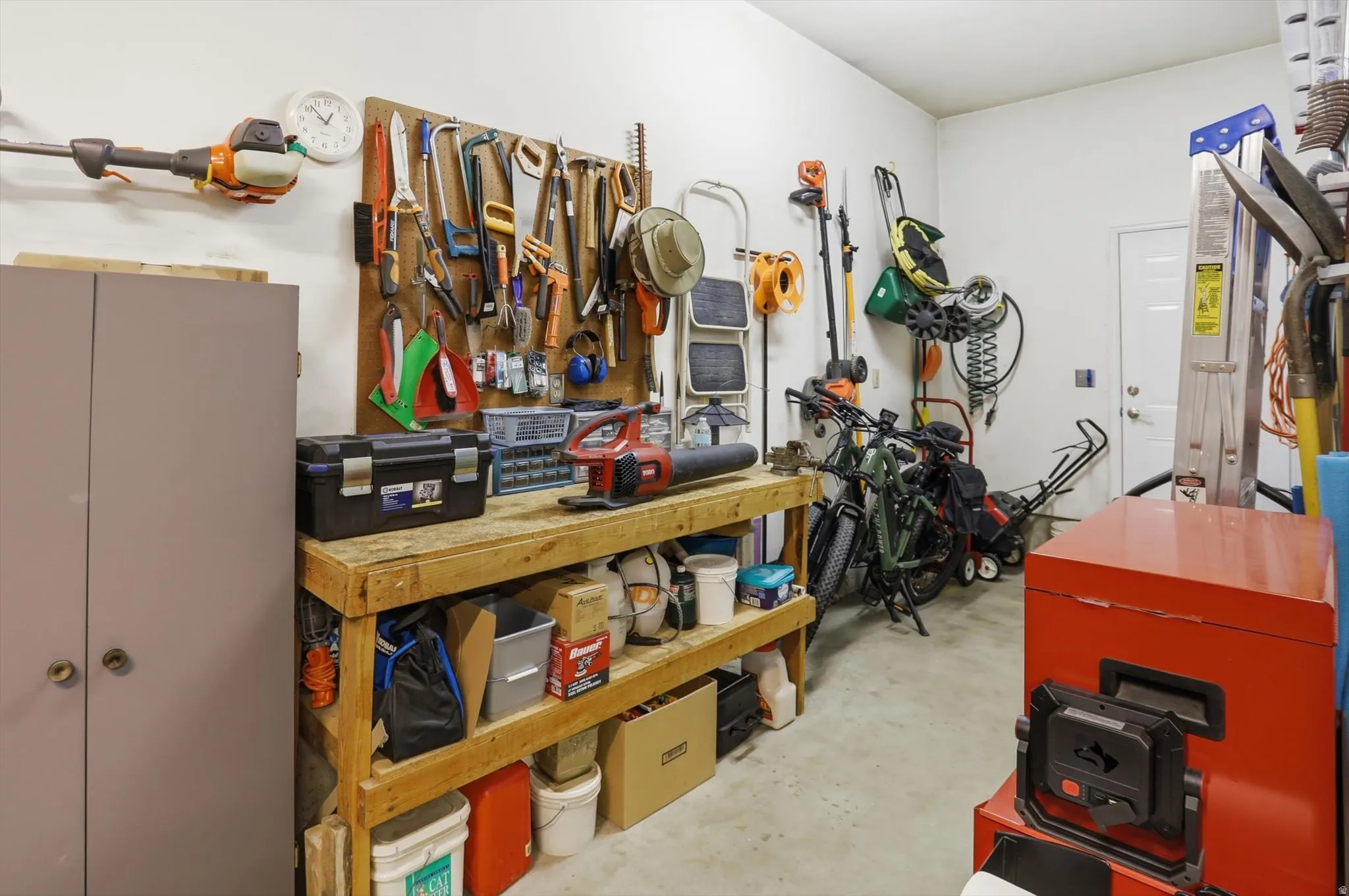 Integrated workbench with pegboard organization, concrete flooring, white walls, and a white interior door