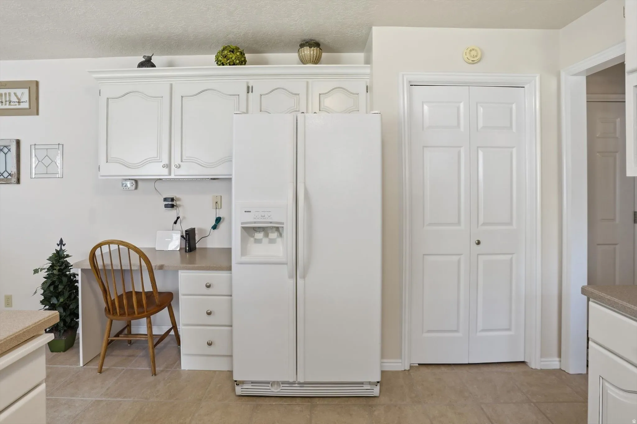Kitchen area featuring a built-in desk, white cabinetry with crown molding, and a side-by-side refrigerator