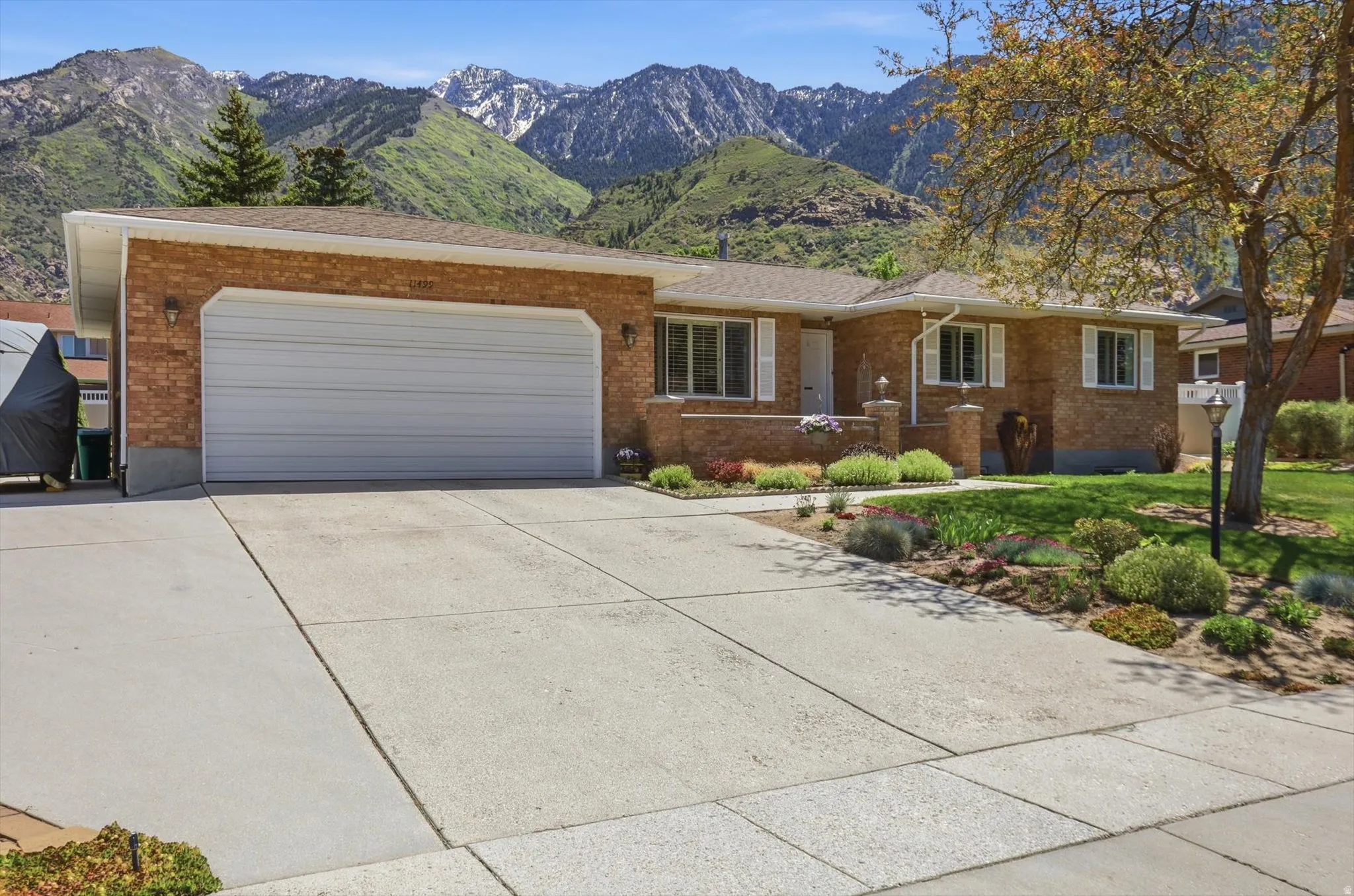 Brick exterior residence featuring a two-car garage, concrete driveway, and established front landscaping