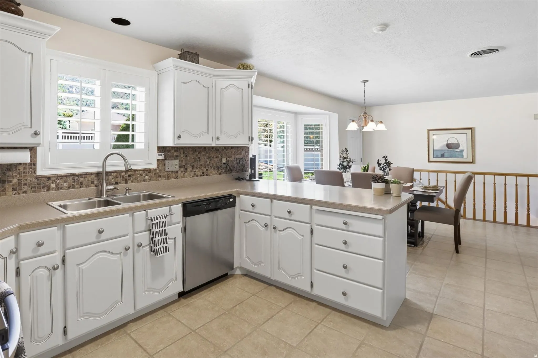 Kitchen featuring white cabinetry, a double basin stainless steel sink, and a mosaic tile backsplash