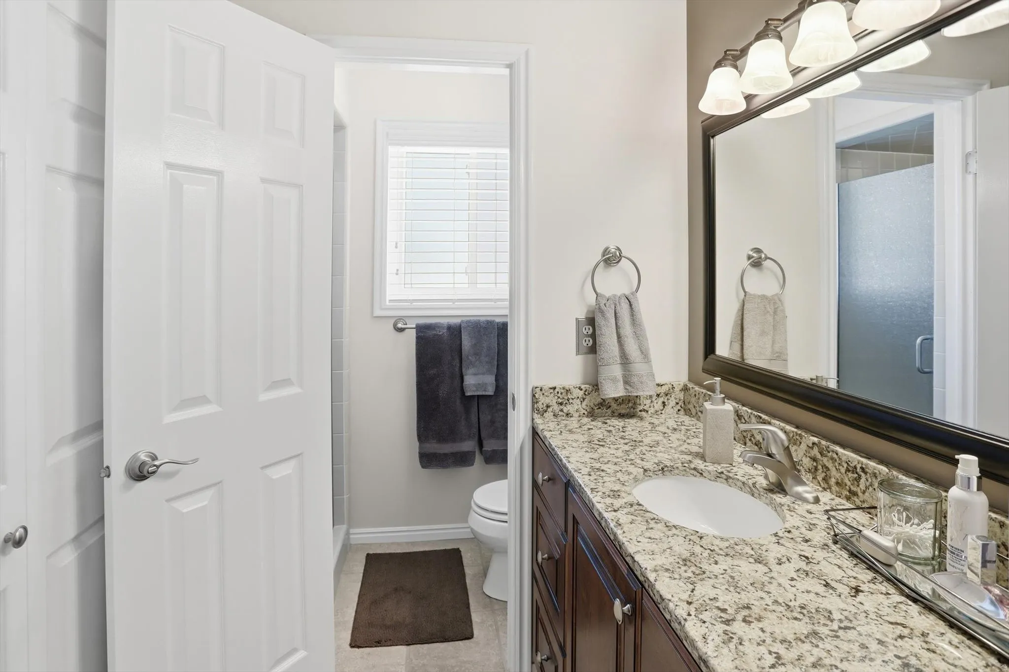 Bathroom featuring a vanity with a light-toned countertop, undermount sink, and dark wood-finish cabinetry