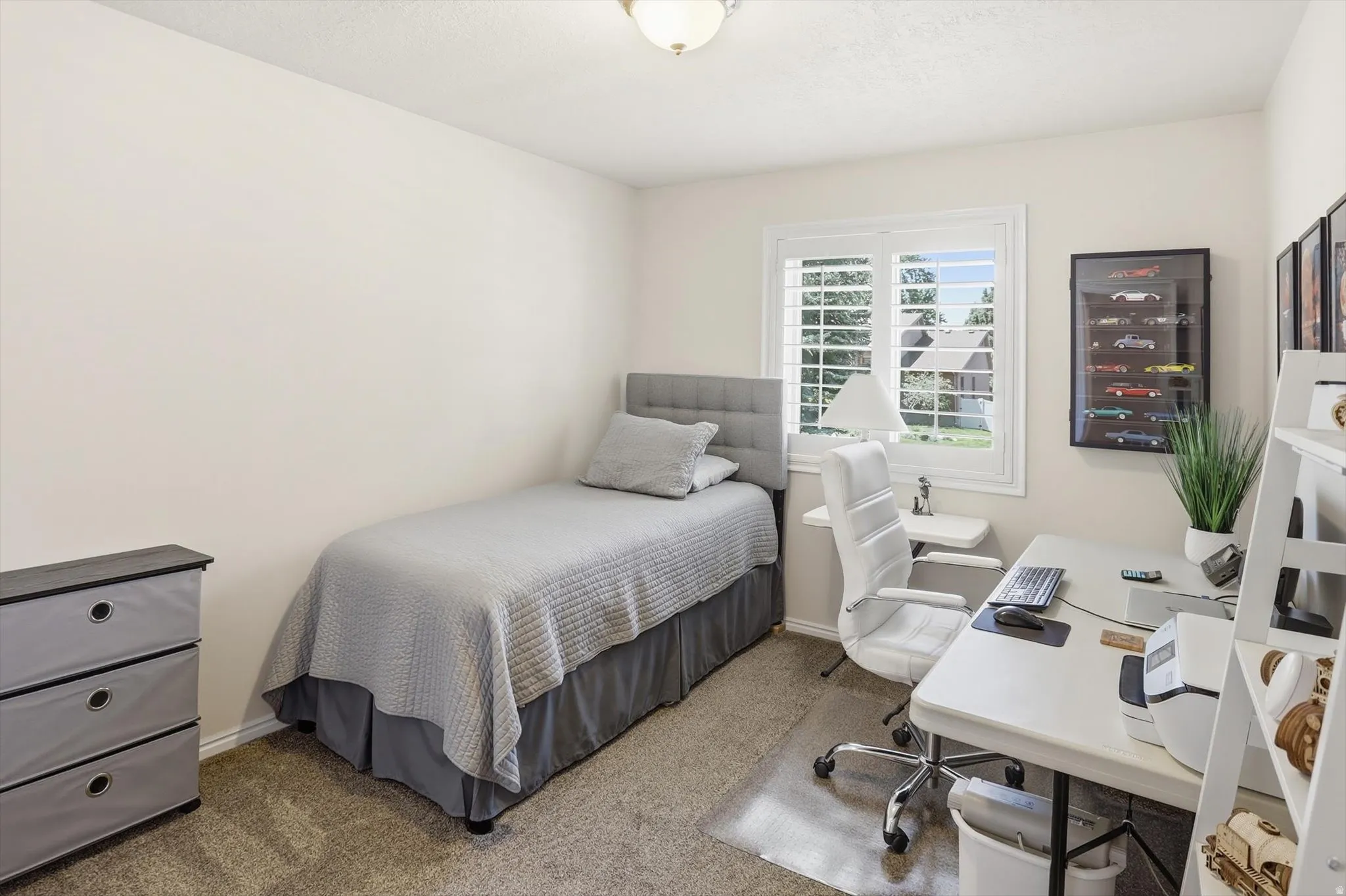Room featuring a white-framed window with plantation shutters, neutral-toned walls, and carpet flooring