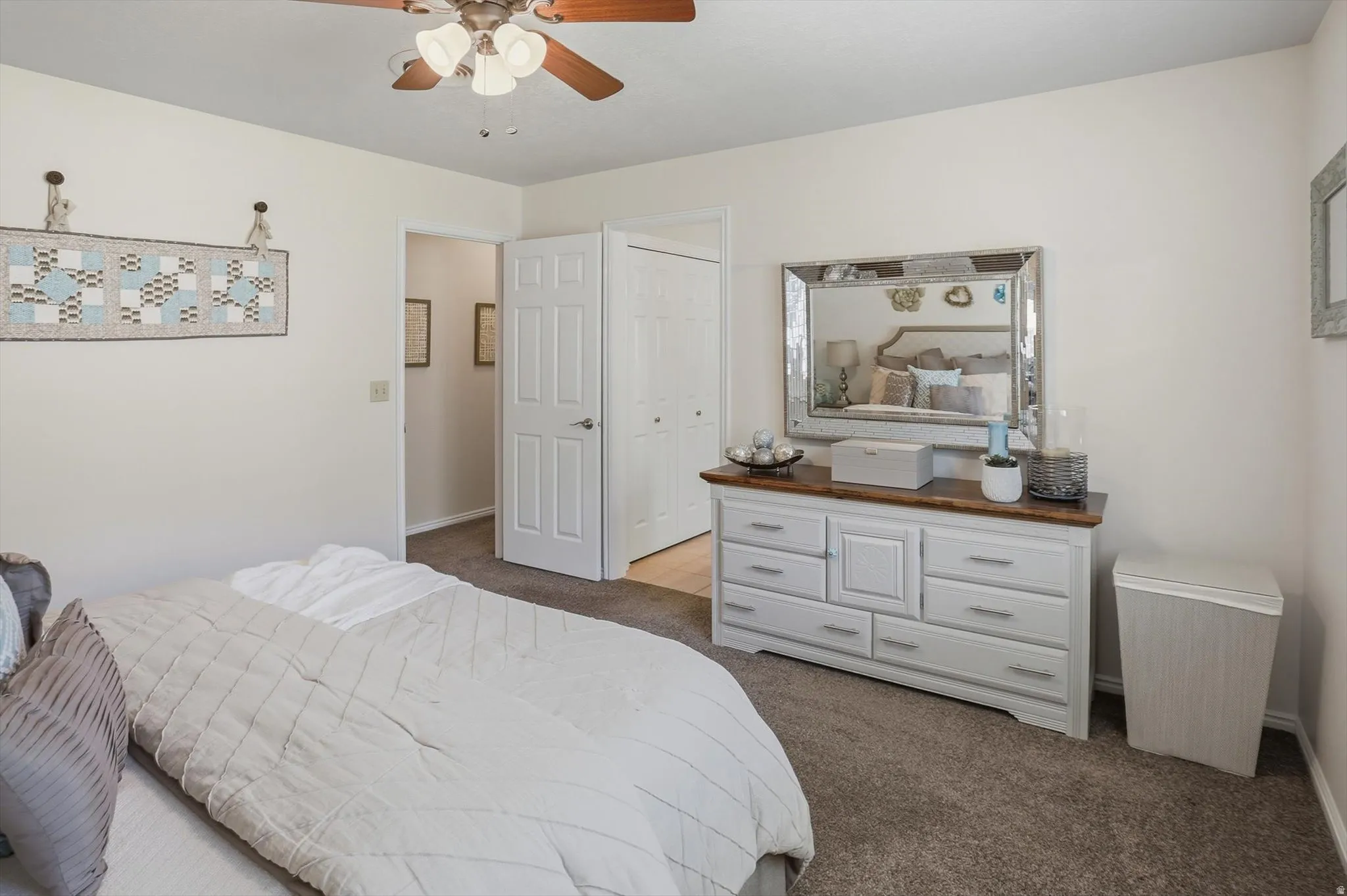 Carpeted flooring, white interior doors, a ceiling fan with light kit, and neutral wall paint