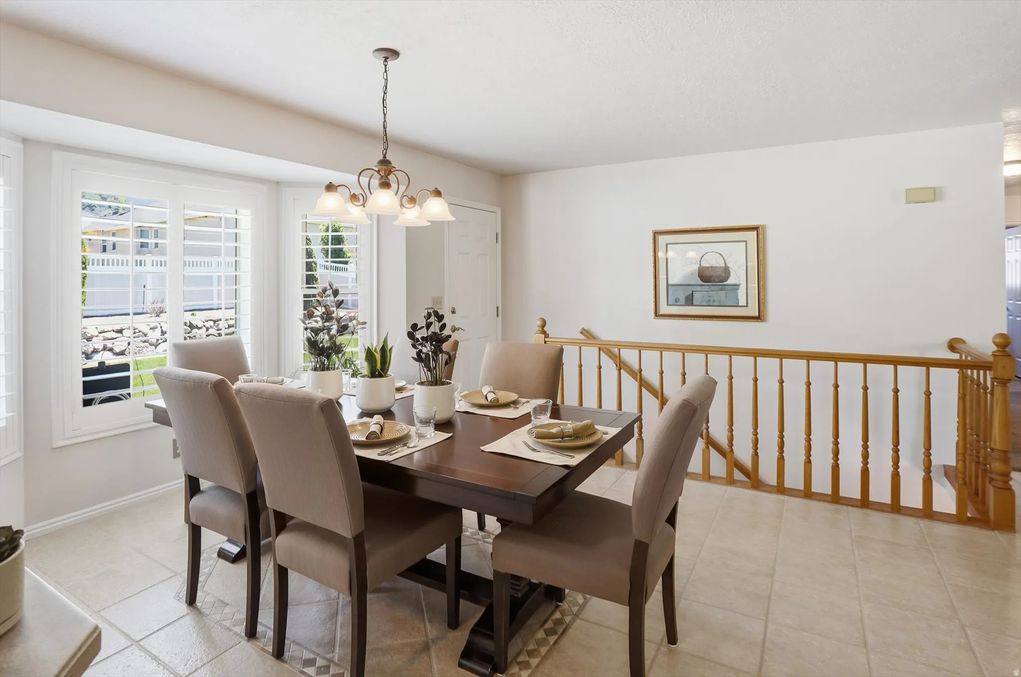 Dining area featuring a bay window with plantation shutters, tile flooring, and a chandelier