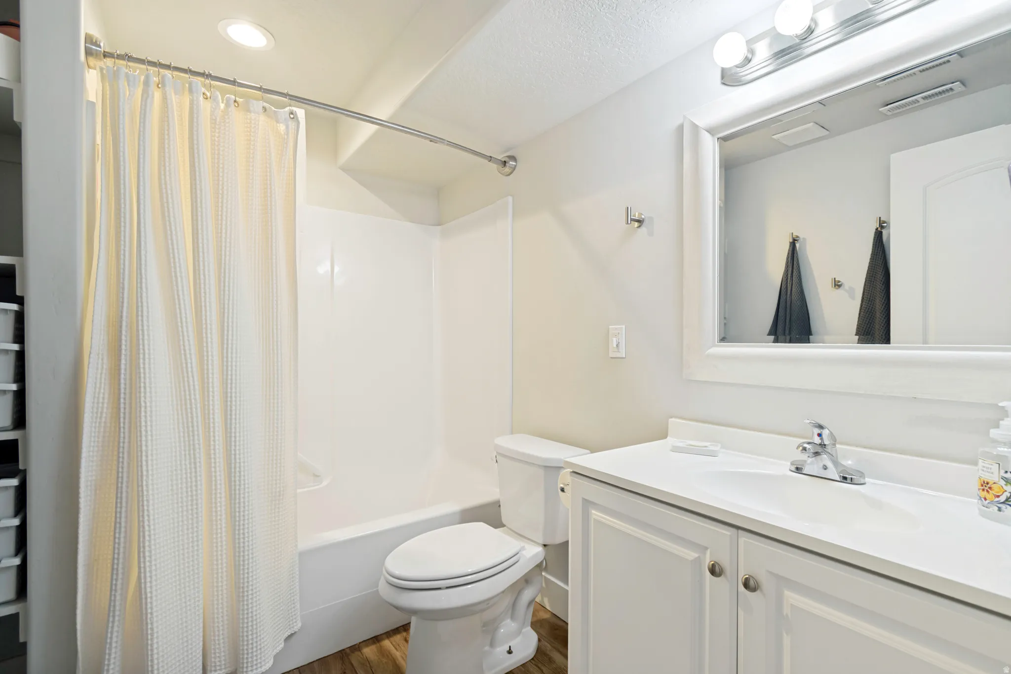 Bright bathroom featuring a white vanity with integrated sink, a framed mirror, and a full bathtub with shower surround