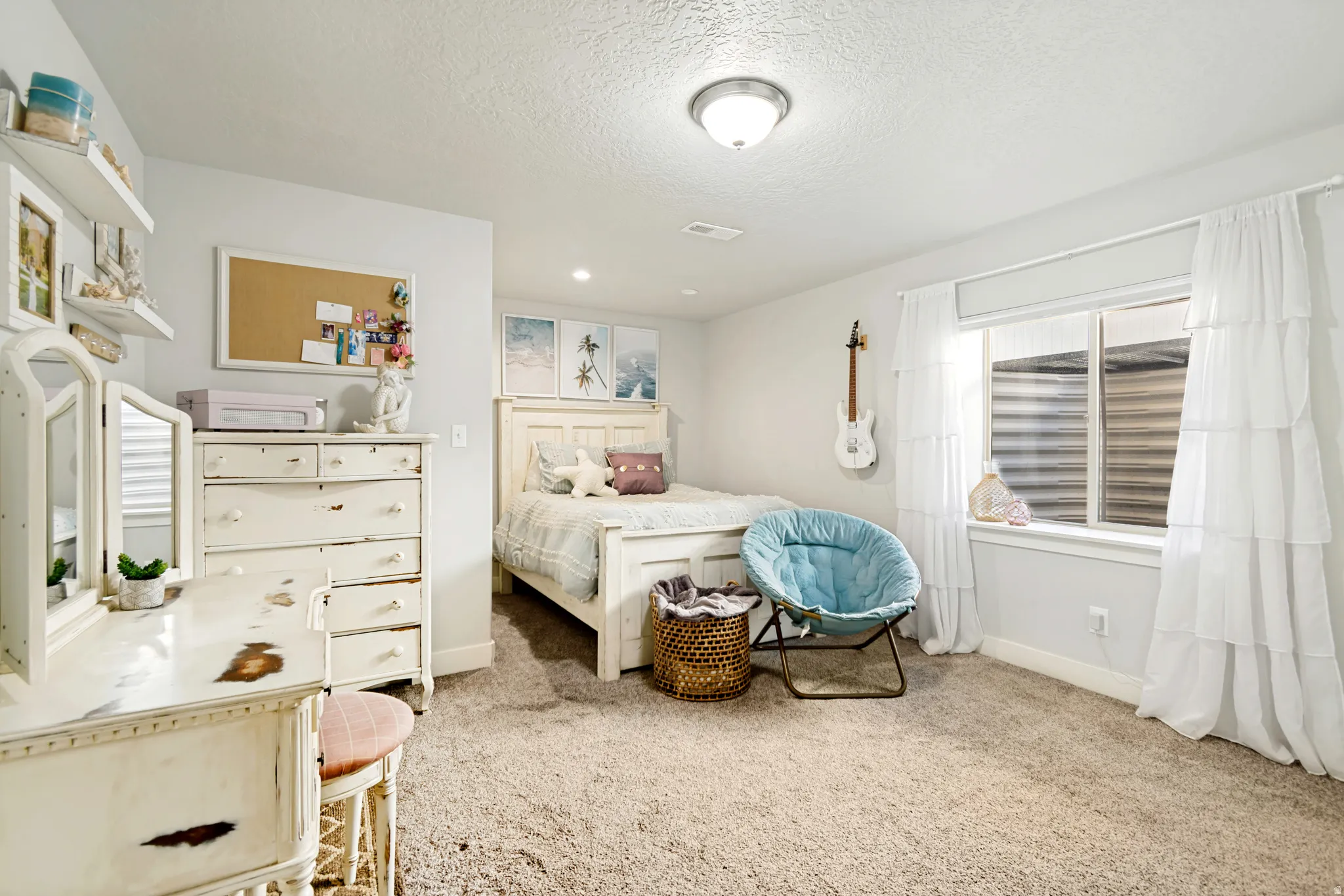 Carpeted interior space featuring a window with white roller shade, white baseboards, and a flush mount ceiling light fixture.