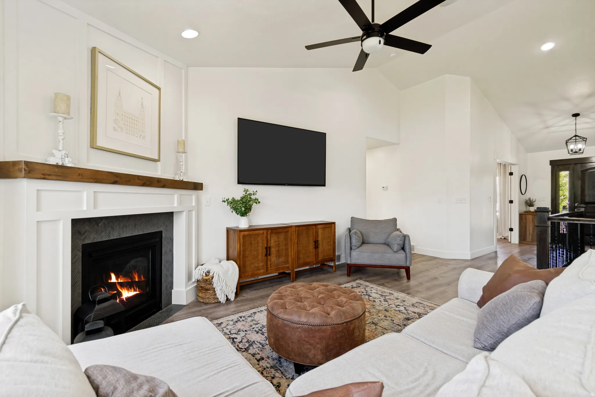 Living area featuring a fireplace with a white mantel and dark tile surround, a built-in television, and vaulted ceilings.