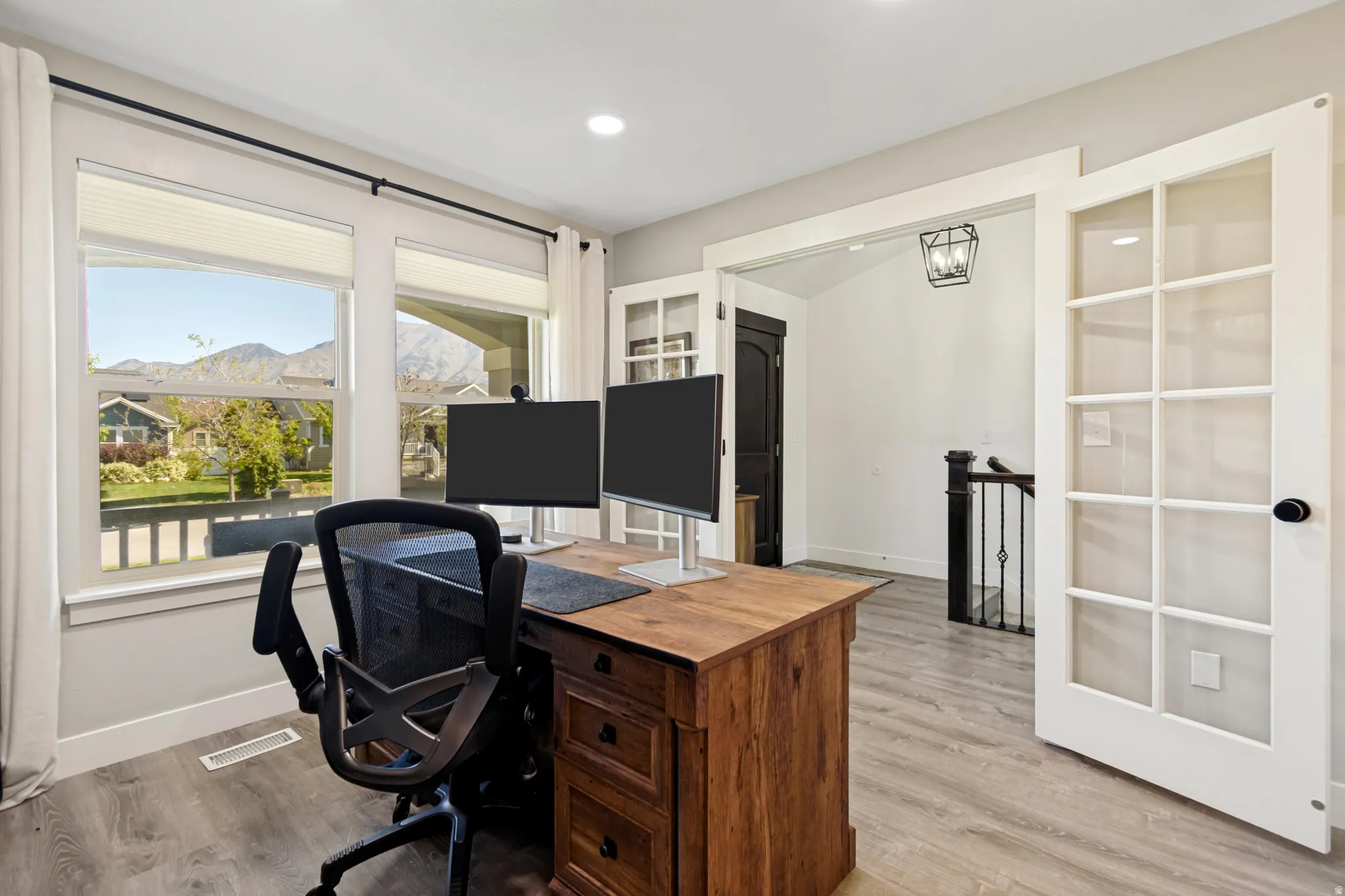 Bright interior space featuring wood-finish flooring and a large window overlooking a mountain range.