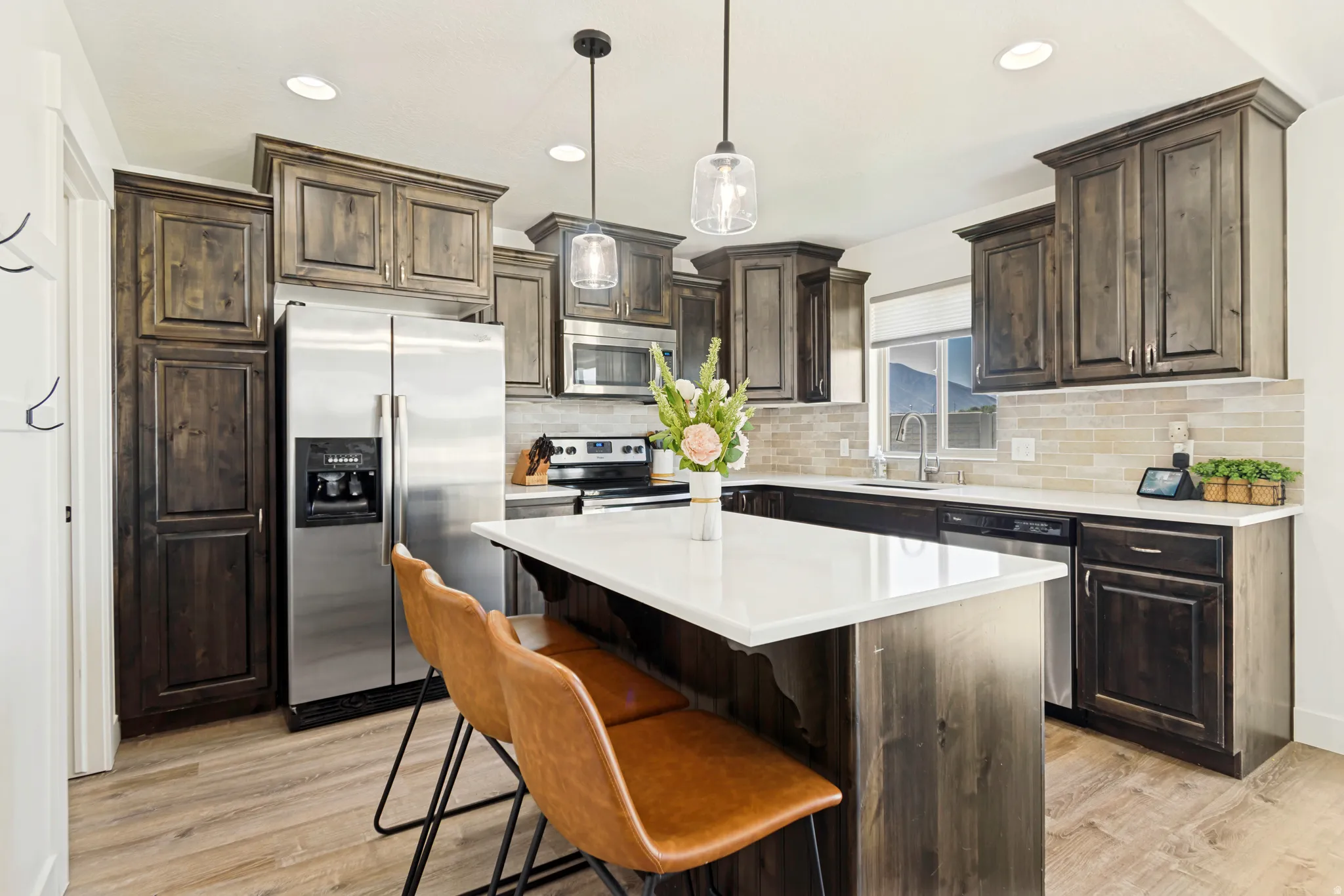 Kitchen featuring wood-finish cabinetry, stainless steel appliances, a center island with white countertop, and recessed lighting.