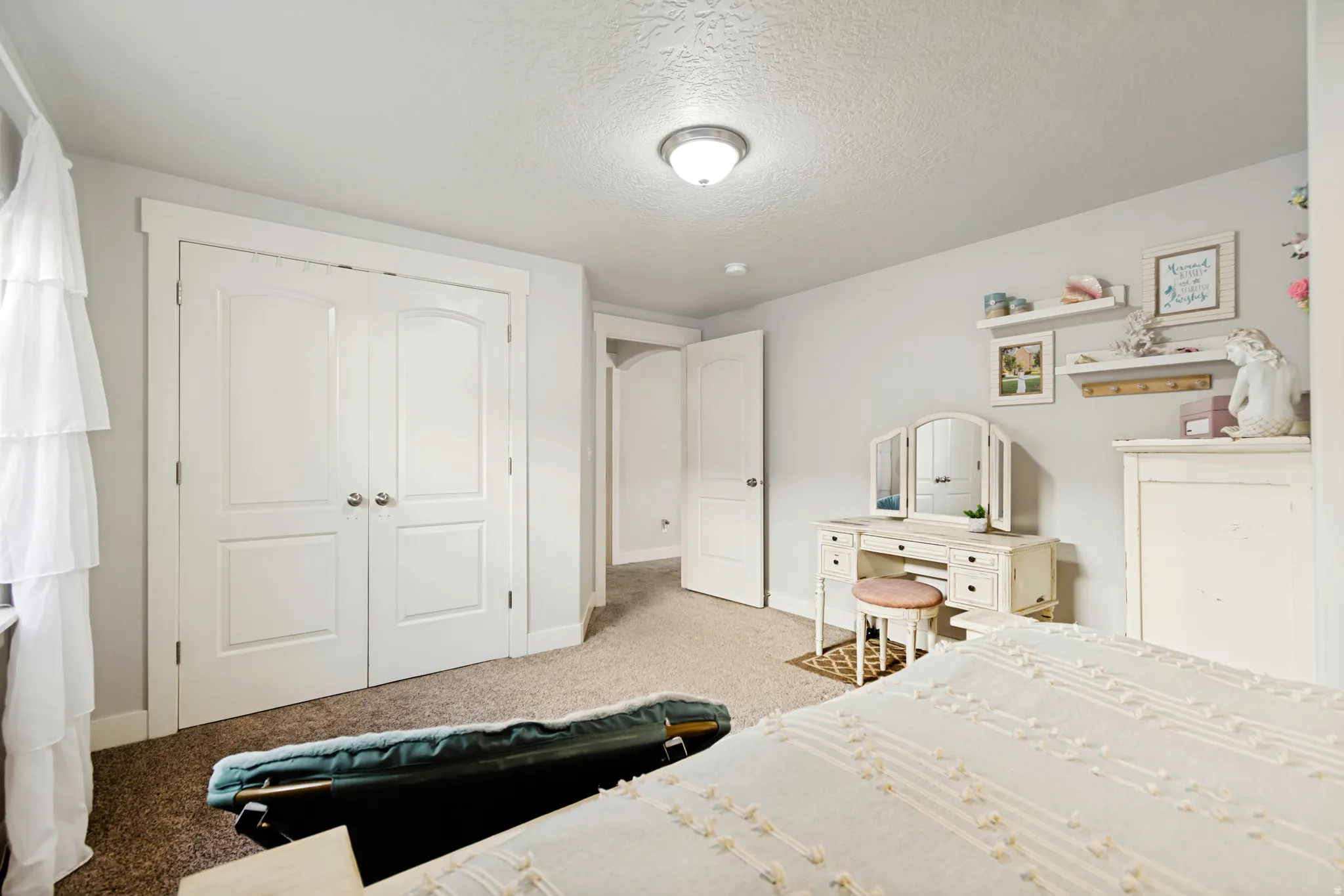 Carpeted room featuring a double-door spacious closet with arched paneling, and white trim.