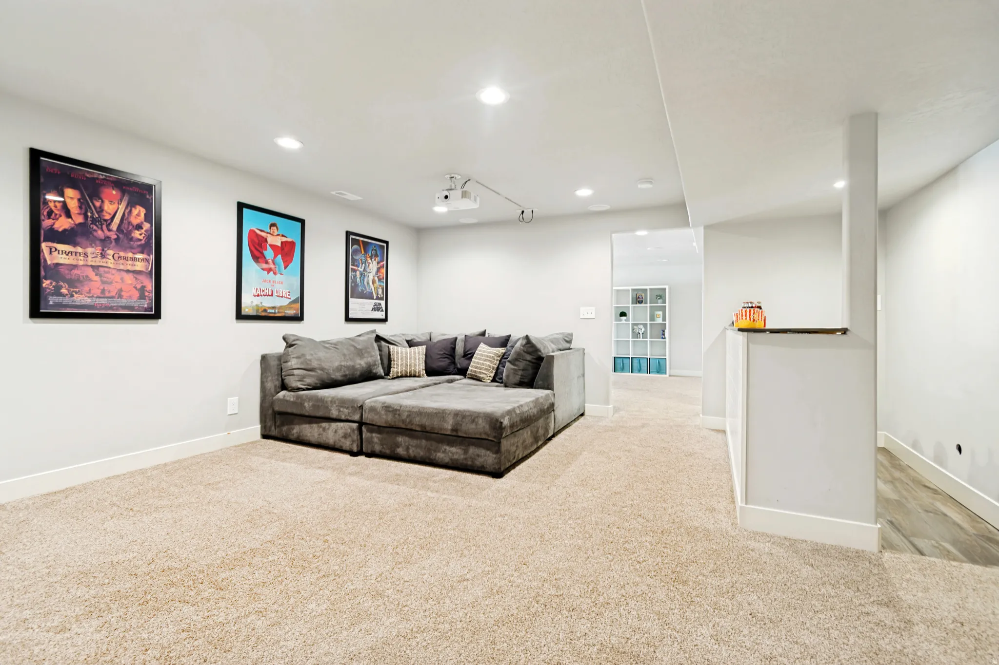 Spacious entertainment area featuring recessed lighting, projector, and light-toned carpeting.