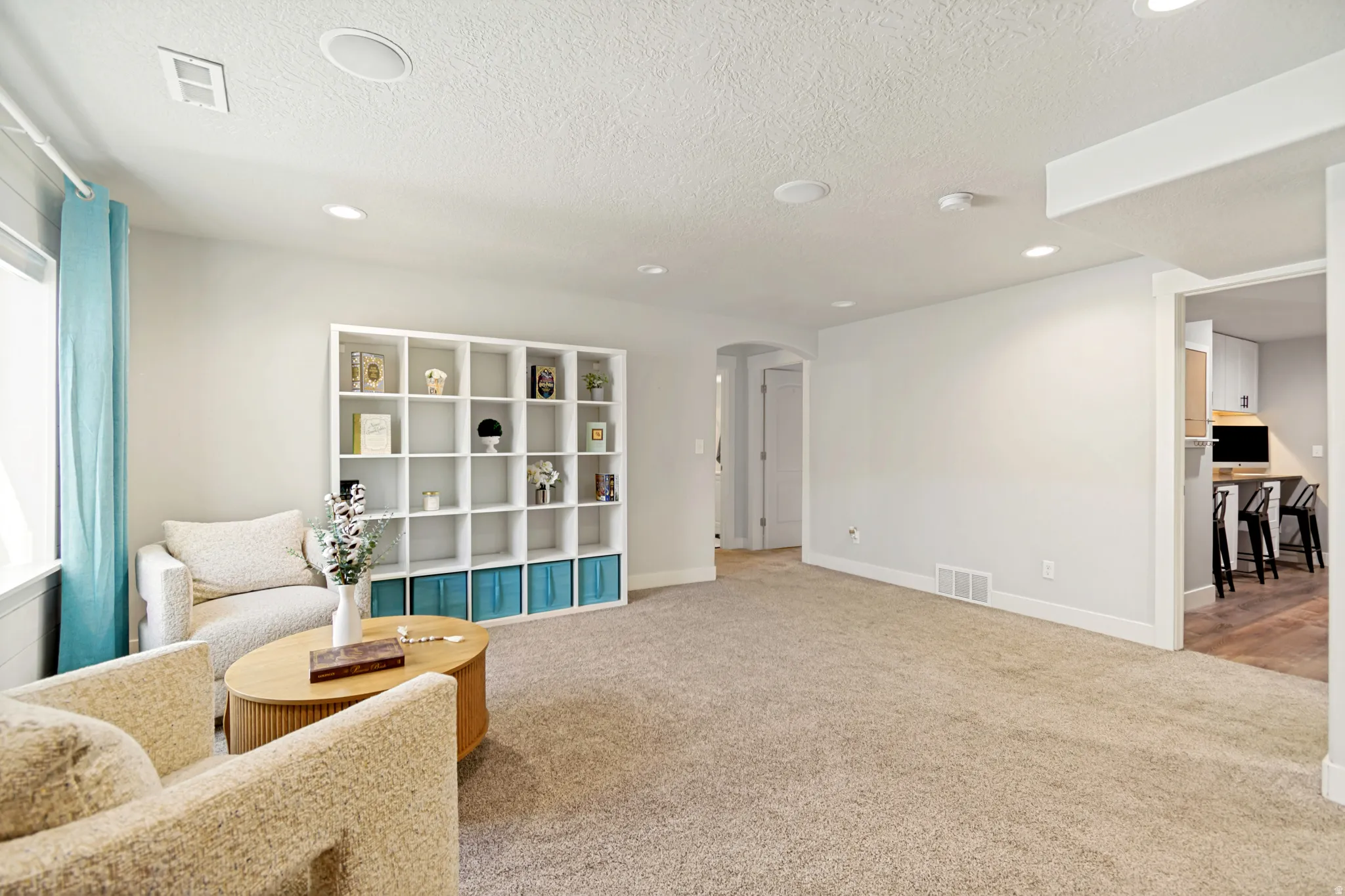 Spacious living area featuring neutral carpeting and light-toned walls.