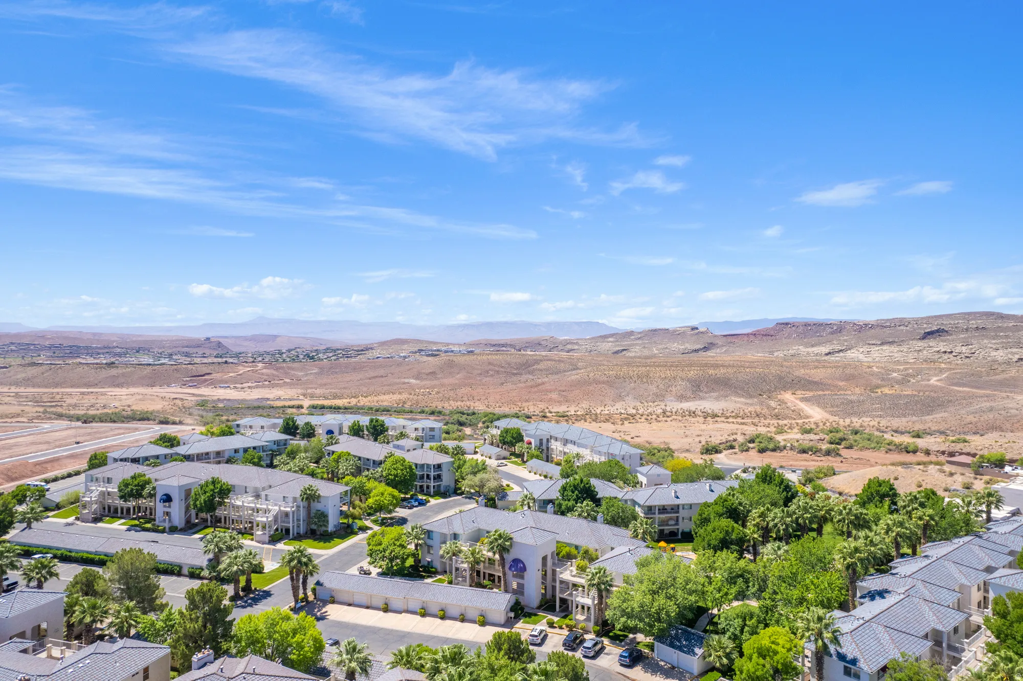 Aerial perspective showcasing a residential community with multiple buildings featuring light-colored exteriors and dark tile roofing