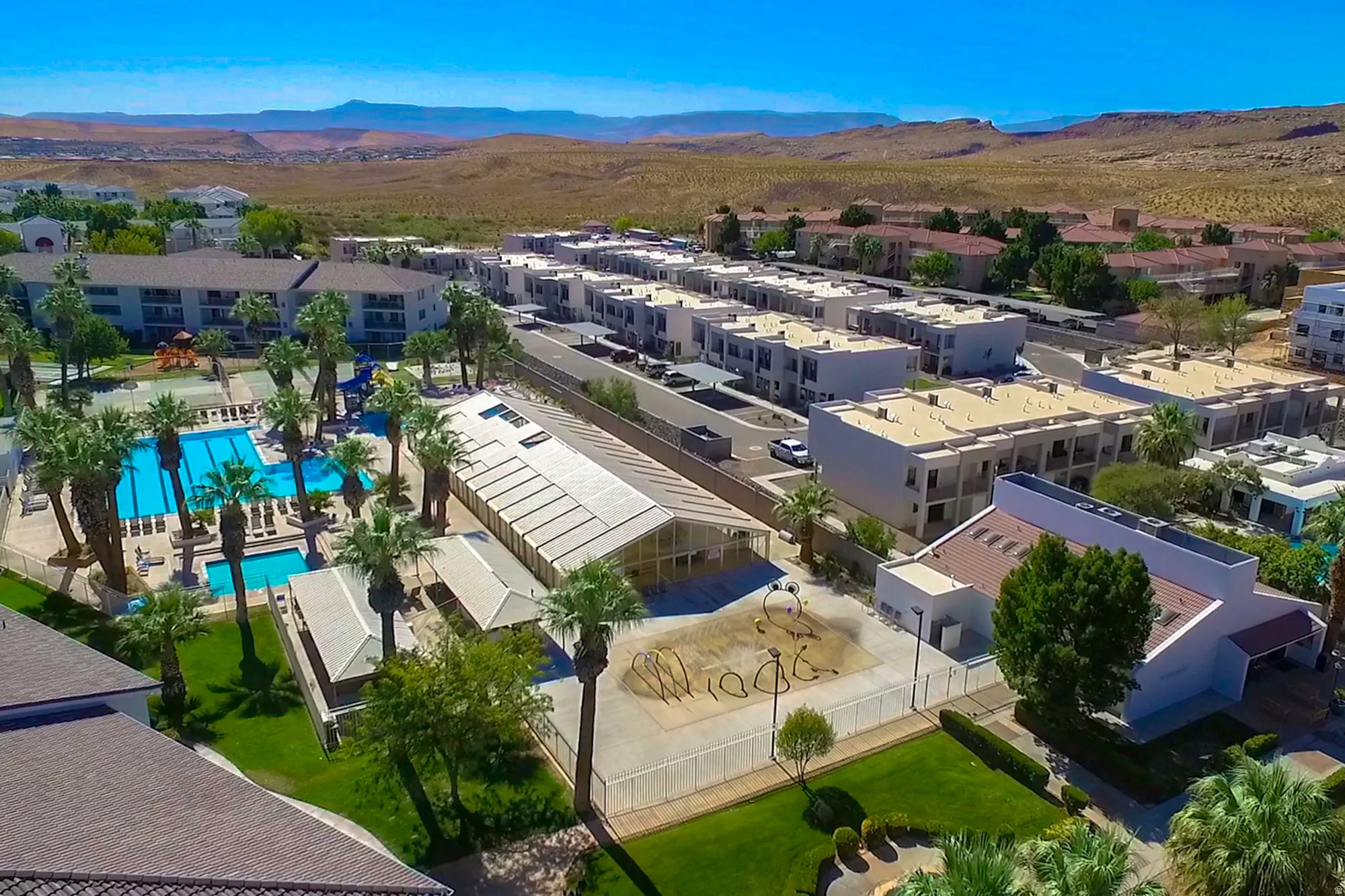 Expansive swimming pool area with multiple rectangular pools and surrounding lounge seating, framed by numerous palm trees