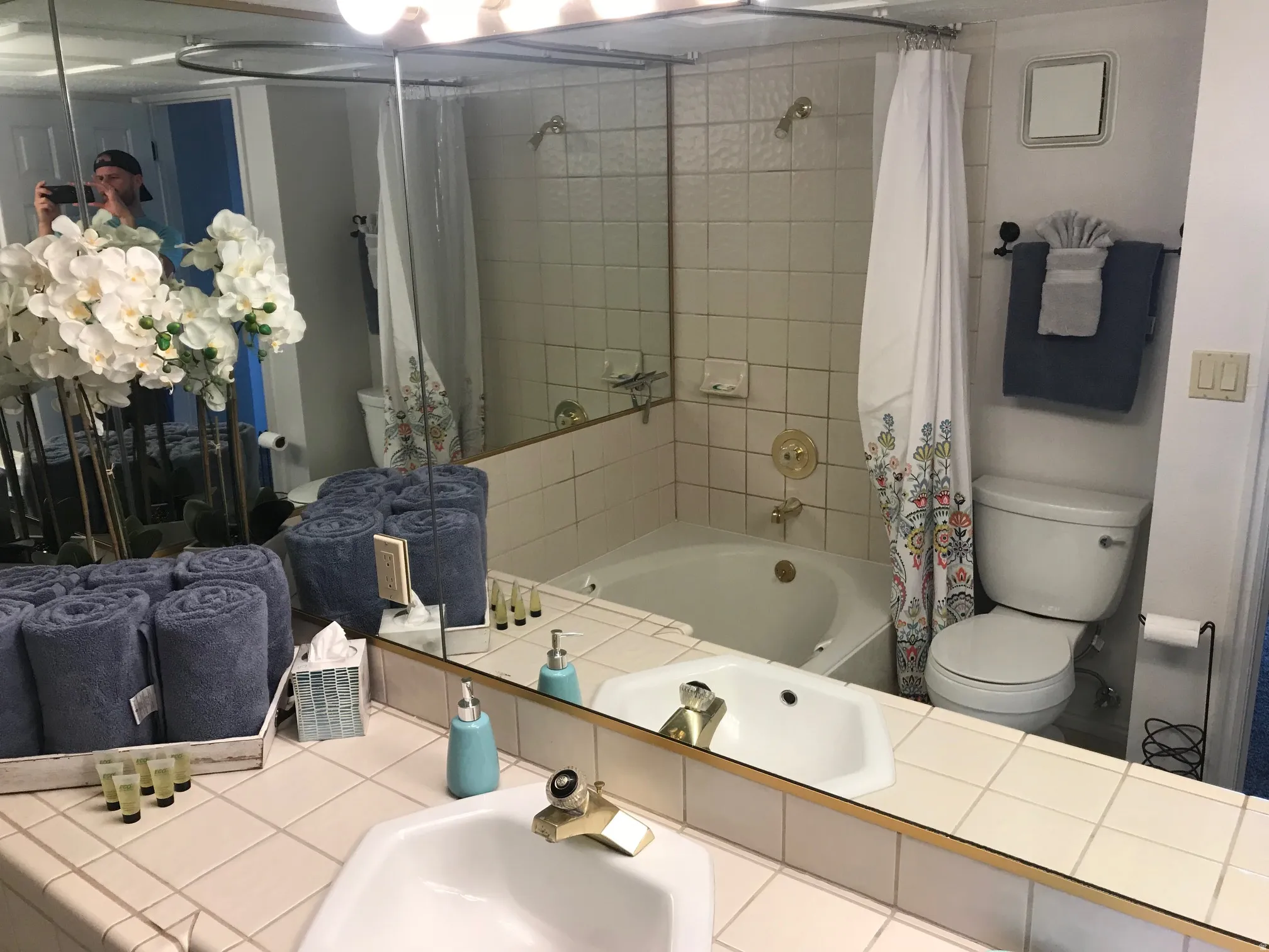 Bathroom featuring a built-in corner soaking tub, a single vanity with an integrated sink, a large wall-mounted mirror, and tile flooring