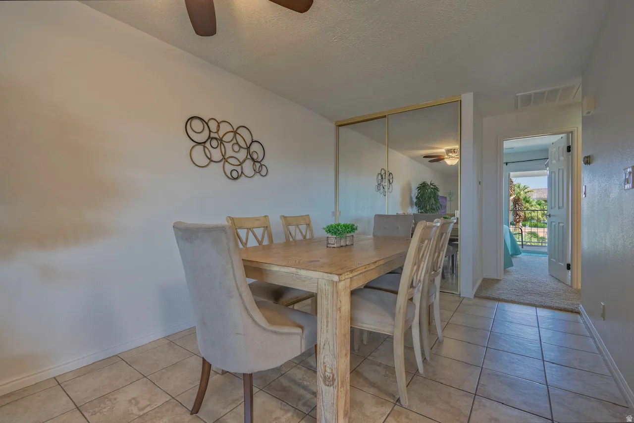 Dining area featuring tiled flooring, a ceiling fan, and a mirrored wall panel
