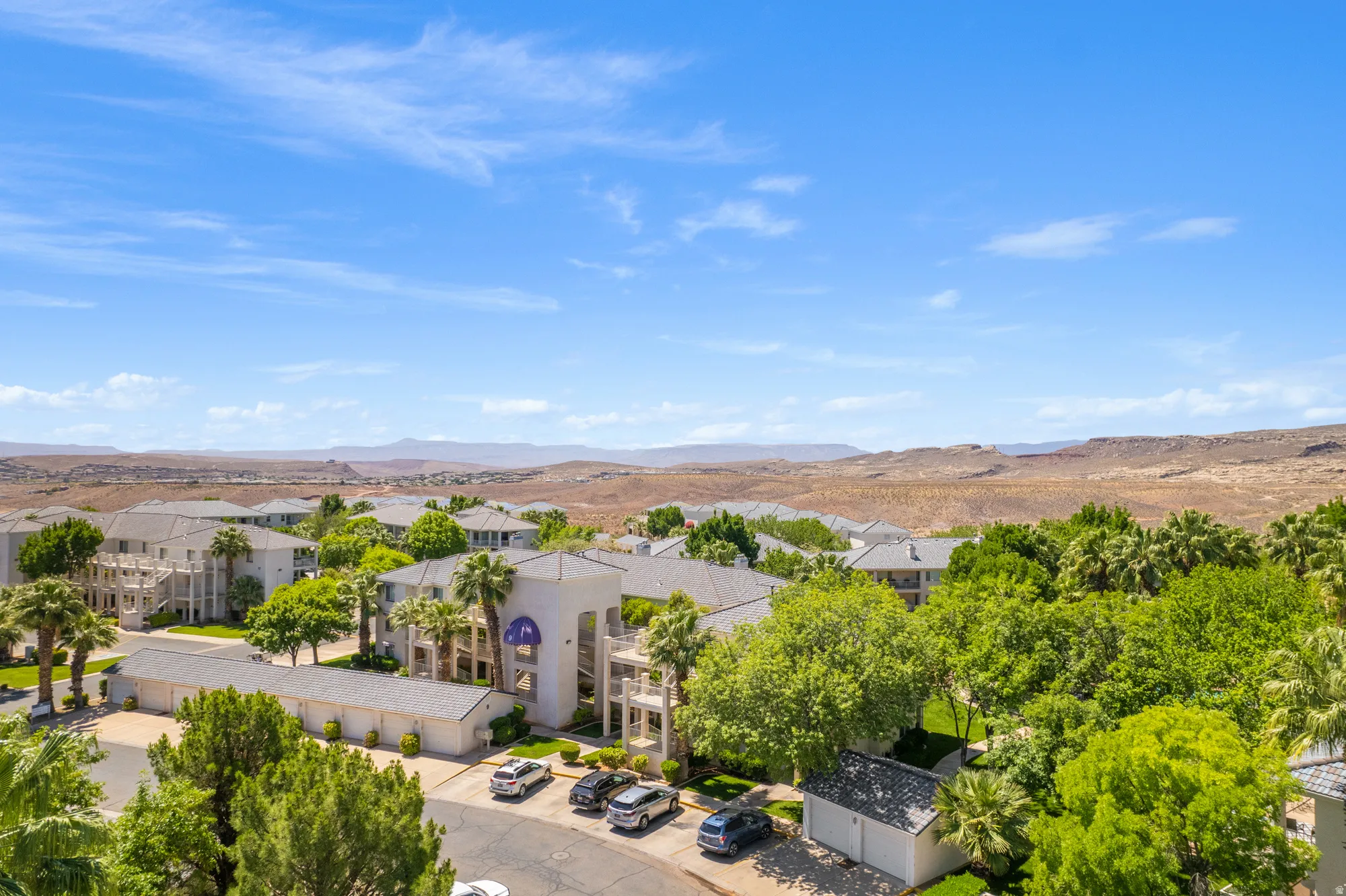 Lush green landscaping surrounding multi-story residential buildings with a desert mountain backdrop