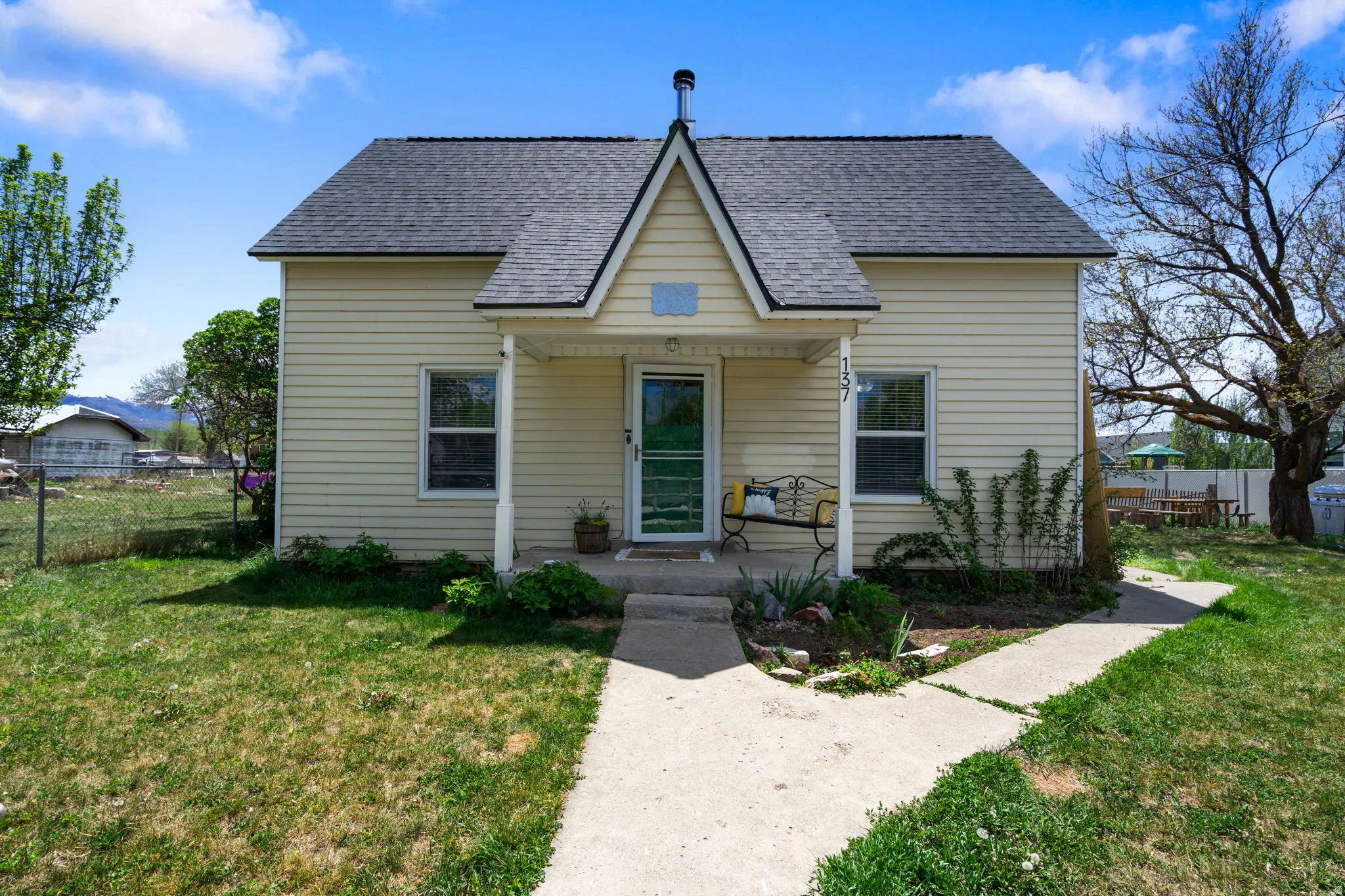 Charming two-story residence featuring light-colored siding, a dark shingled roof, and a welcoming covered front porch
