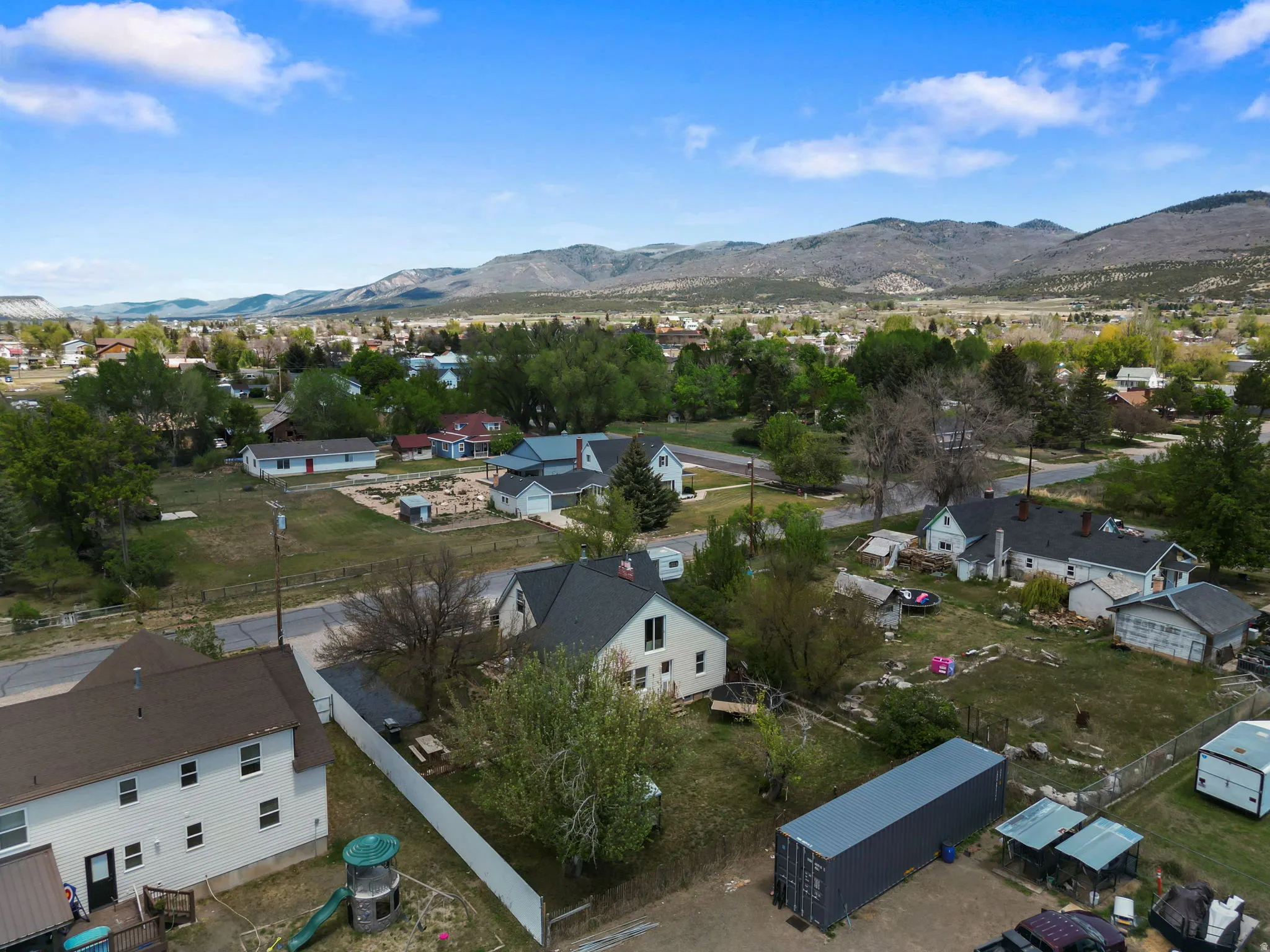 Residential neighborhood with established homes, mature trees, and mountainous terrain in the background