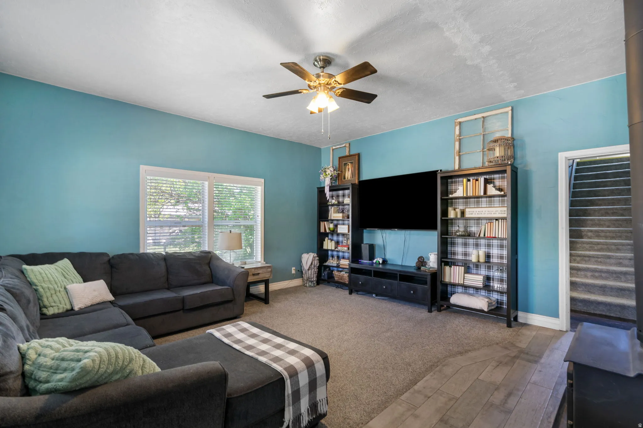 Living area featuring a ceiling fan, window with blinds, and wood-finish flooring