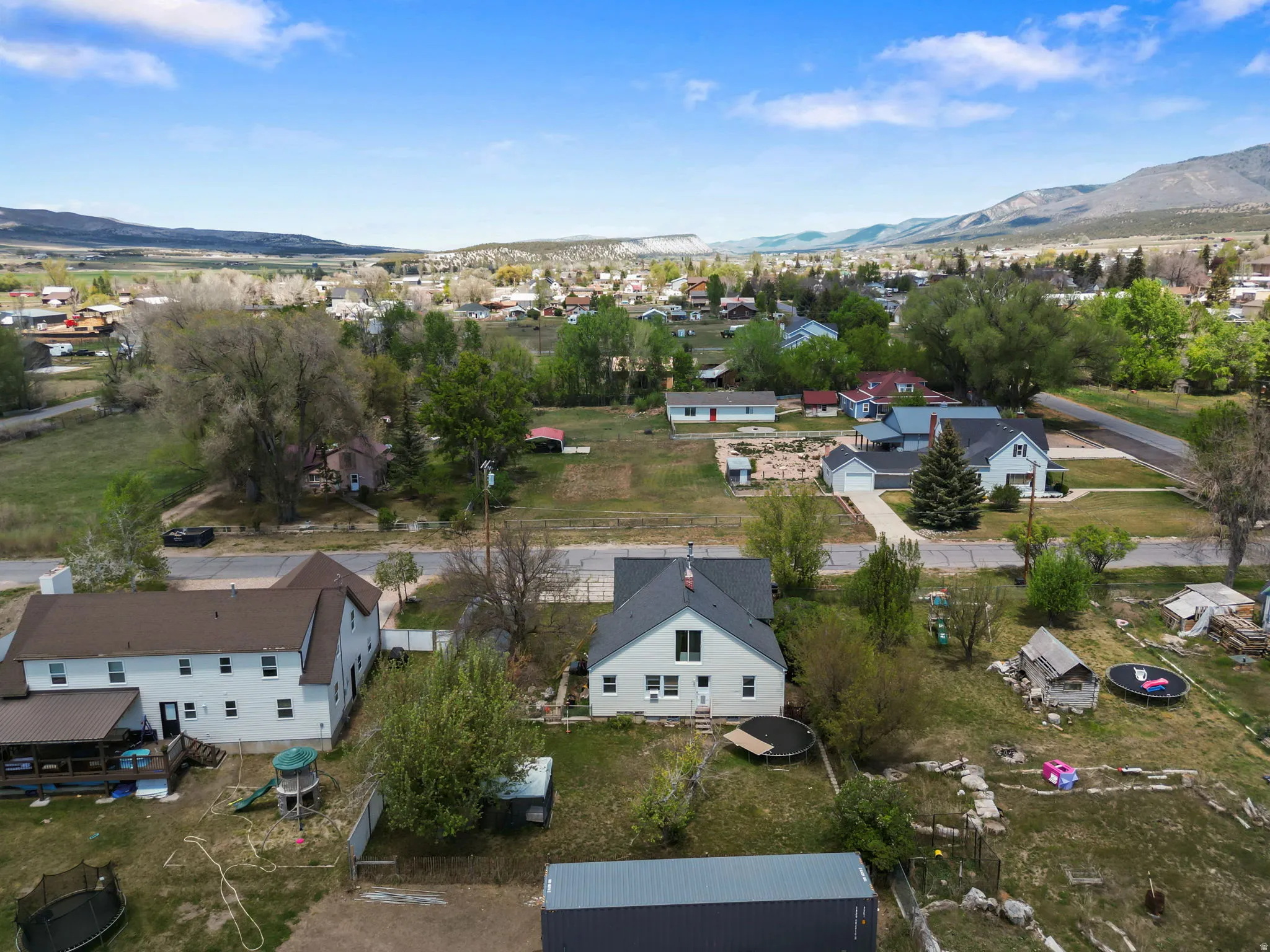 Aerial perspective showcasing a residential area with a prominent white two-story home featuring a dark roof
