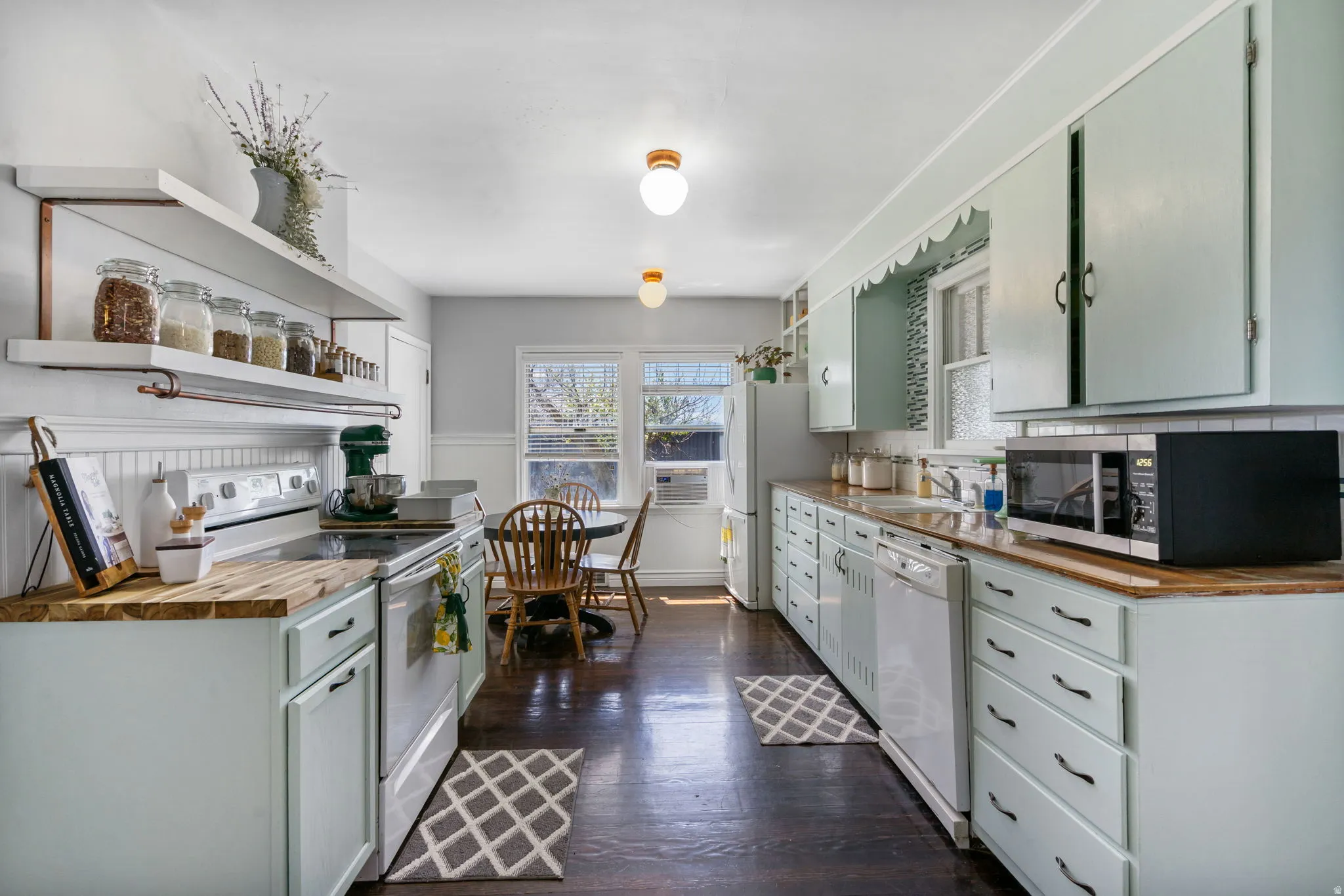 Kitchen featuring light blue cabinetry with dark hardware, butcher block countertops, an electric range, and a built-in dishwasher