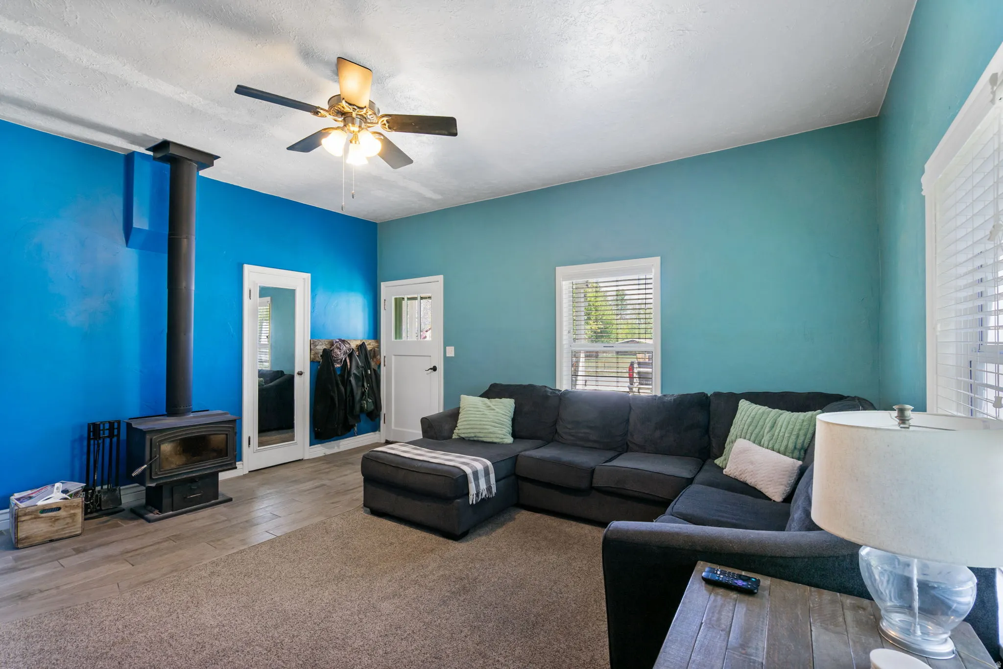 Living space featuring a wood-burning stove and a ceiling fan with integrated lighting