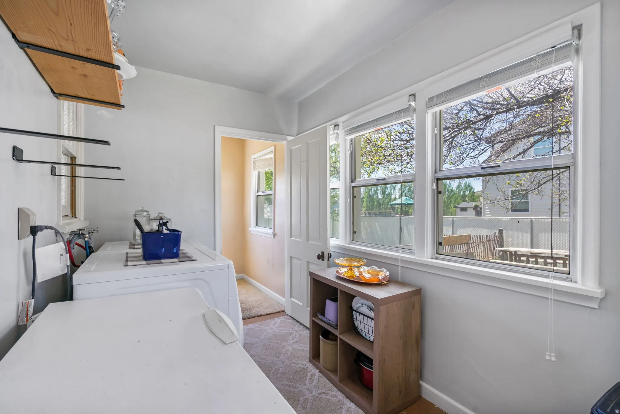 Bright utility room with multiple windows, light-colored walls, and a wood-finish shelving unit