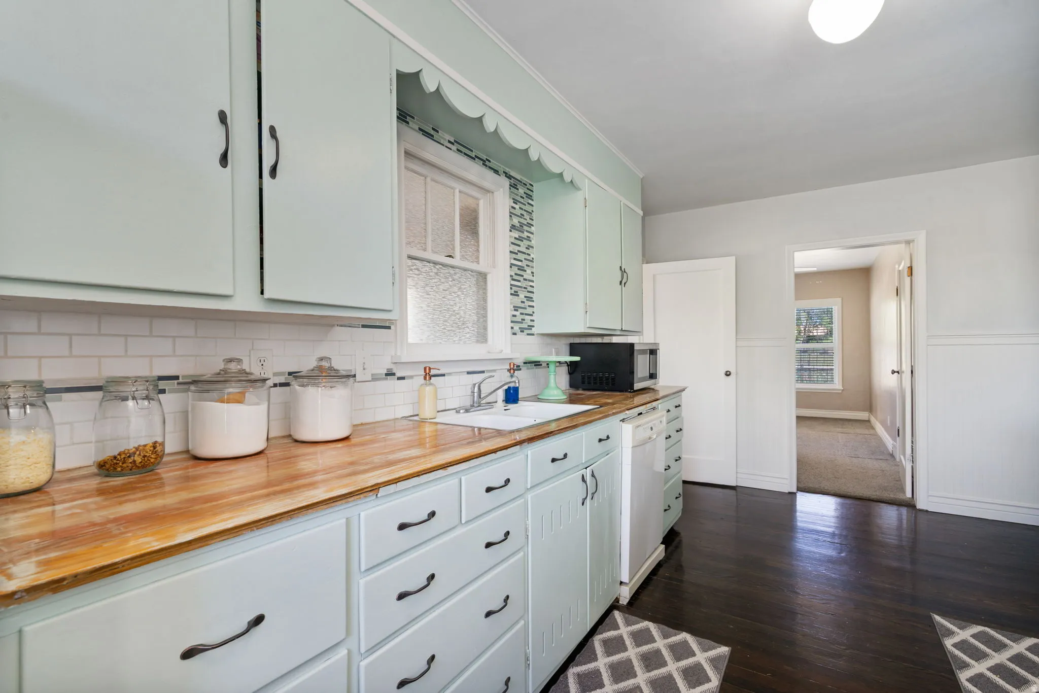 Kitchen featuring light blue cabinetry, wood-finish countertops, and white subway tile backsplash