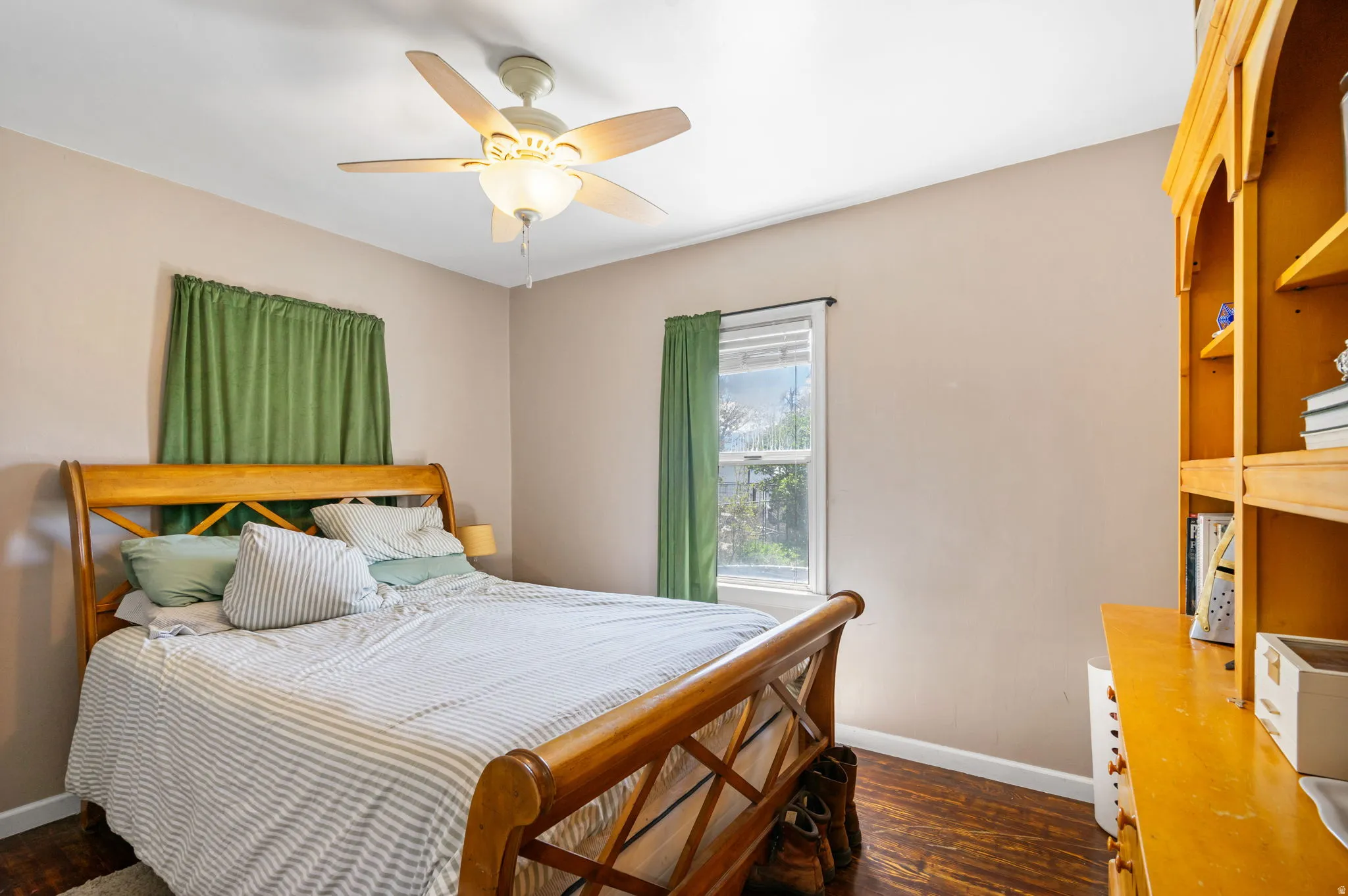Bedroom featuring a ceiling fan with integrated lighting, a window with natural light, and wood-finish flooring