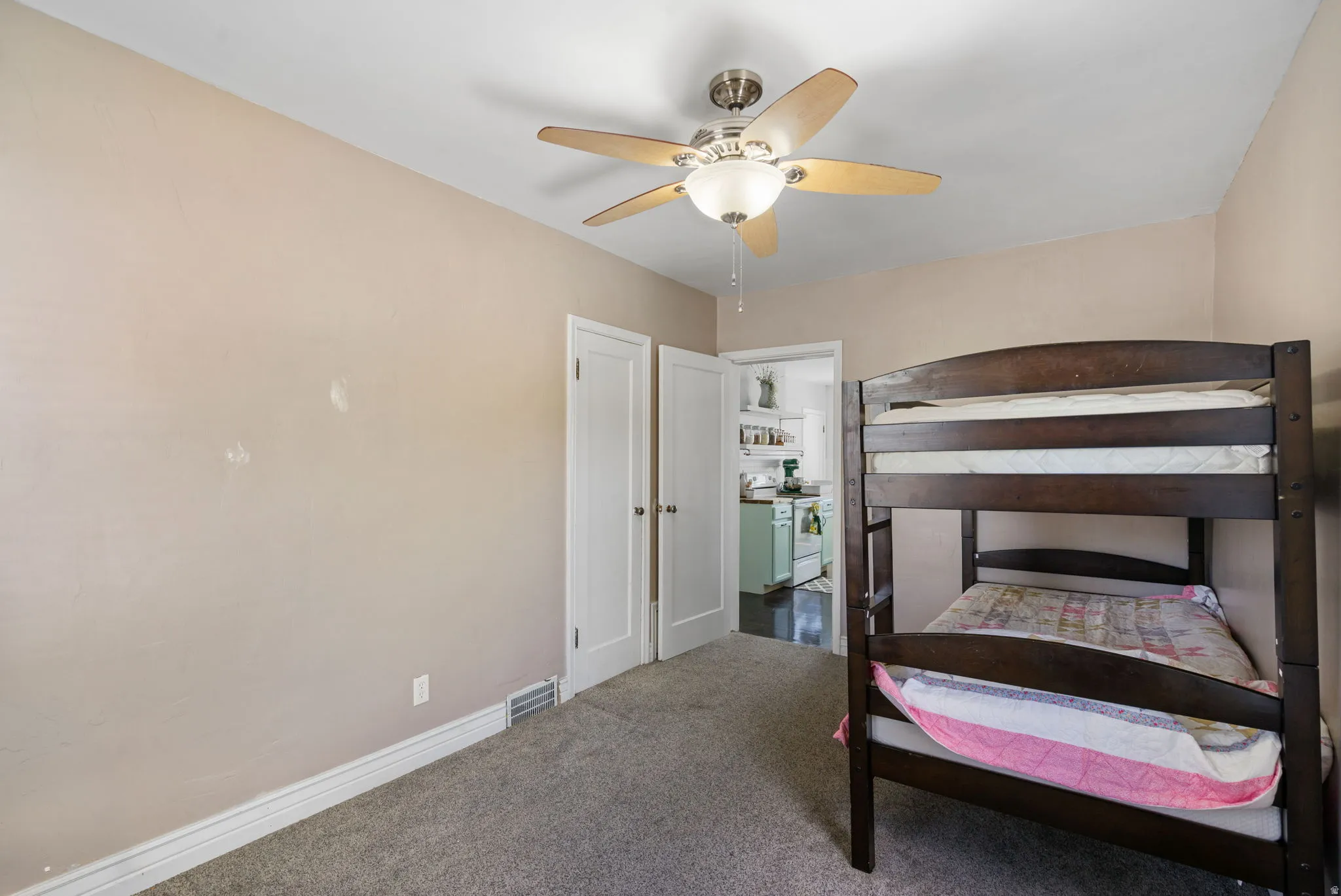Carpeted room featuring a ceiling fan with light fixture, painted walls, and white trim