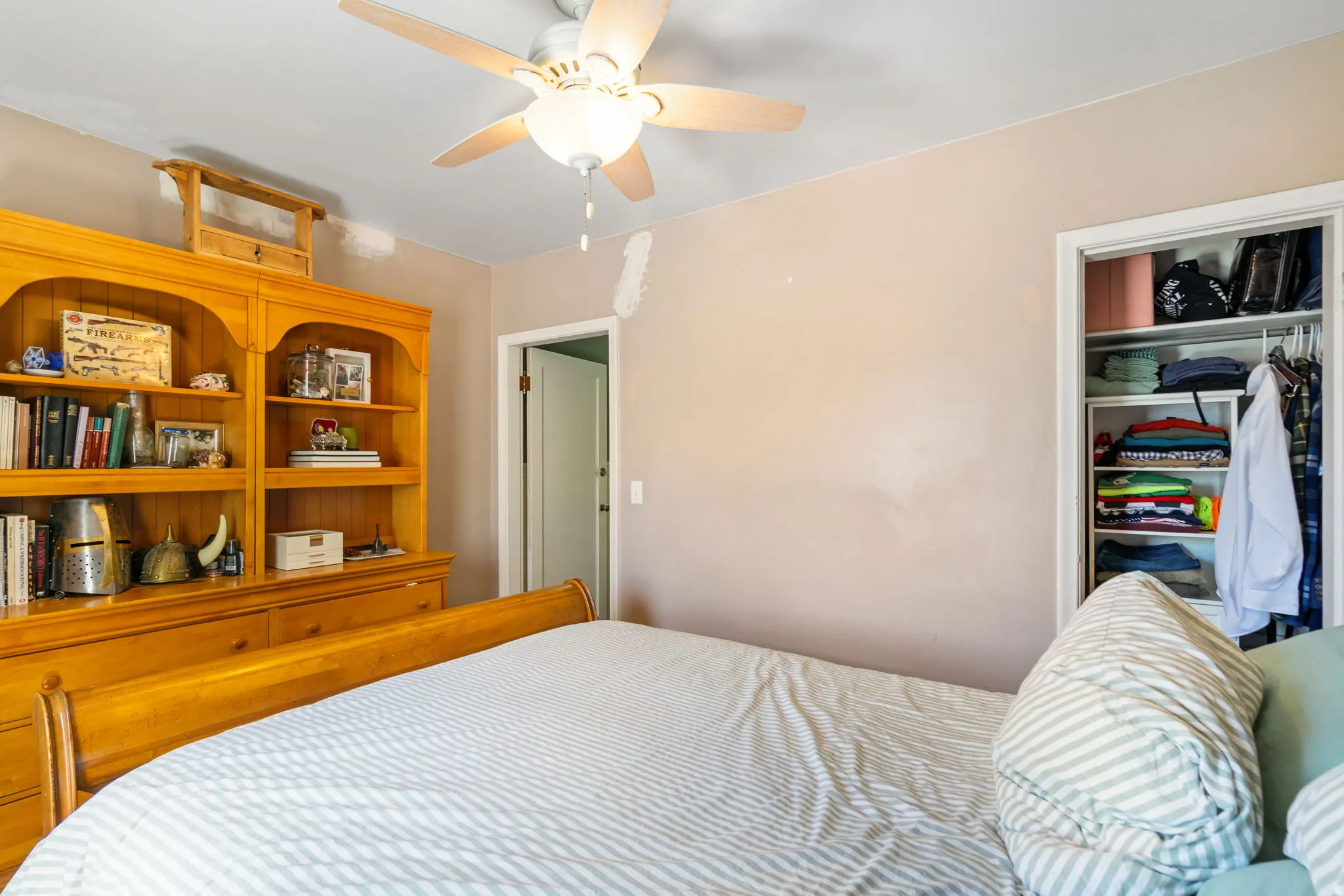 Recessed closet with built-in shelving, ceiling fan light fixture, and wood-finish door frame