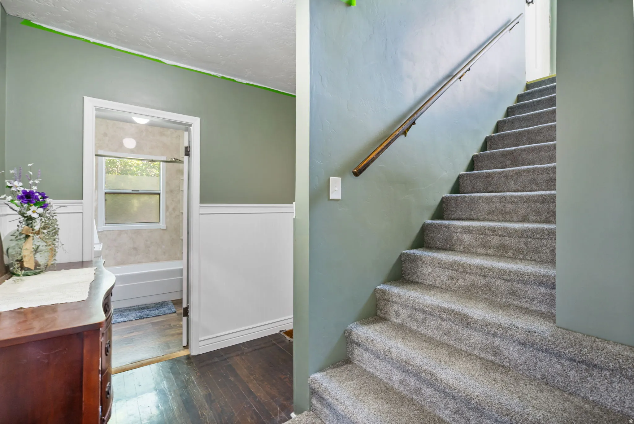 Carpeted staircase with a wooden handrail, leading to an upper level