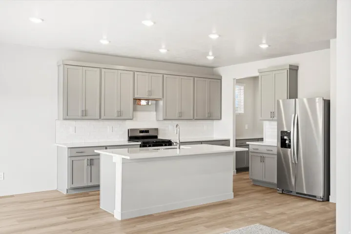 Modern kitchen featuring recessed lighting, light gray cabinetry, white subway tile backsplash, and stainless steel appliances