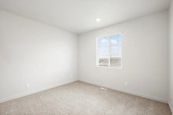 Light-filled room featuring neutral-toned walls, recessed lighting, and carpet flooring