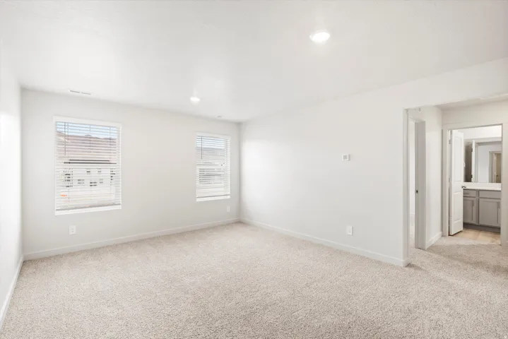 Bright room with neutral carpet flooring and white walls, featuring two windows with blinds