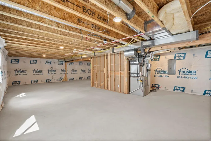 Unfinished basement with exposed wood joists and concrete flooring