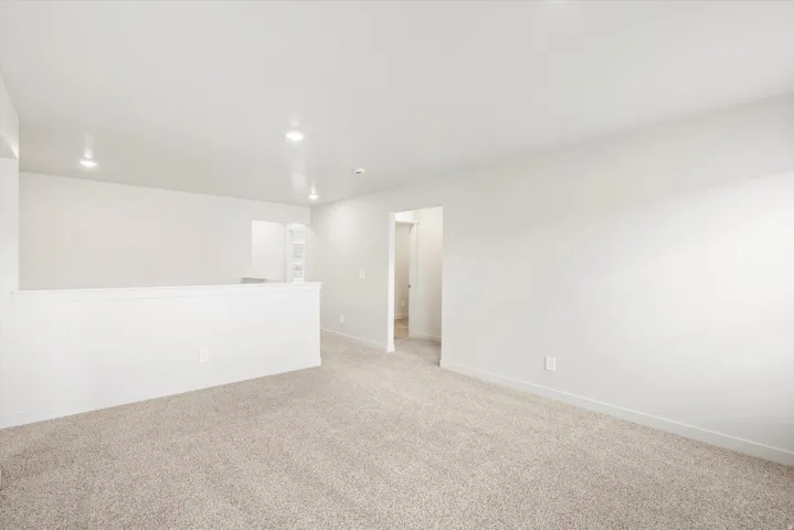 Carpeted open-concept room featuring recessed lighting, neutral wall tones, and white trim