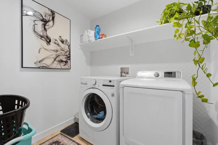 Dedicated laundry space featuring a front-load washer, a dryer, and a wall-mounted storage shelf