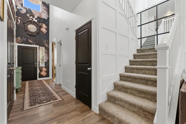 Two-story foyer featuring wood-finish flooring and a staircase with carpeted treads