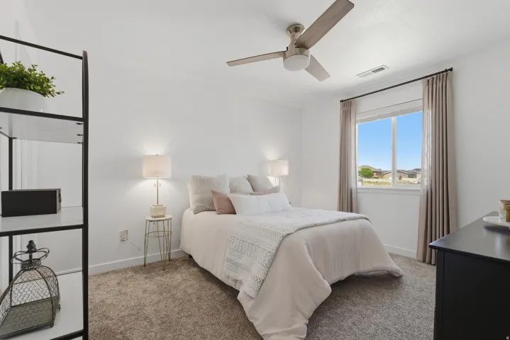 Carpeted room featuring a ceiling fan with light, a window with drapery, and a built-in shelving unit