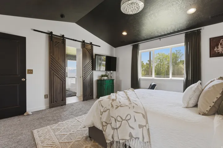 Vaulted ceiling with textured finish, recessed lighting, and a modern chandelier